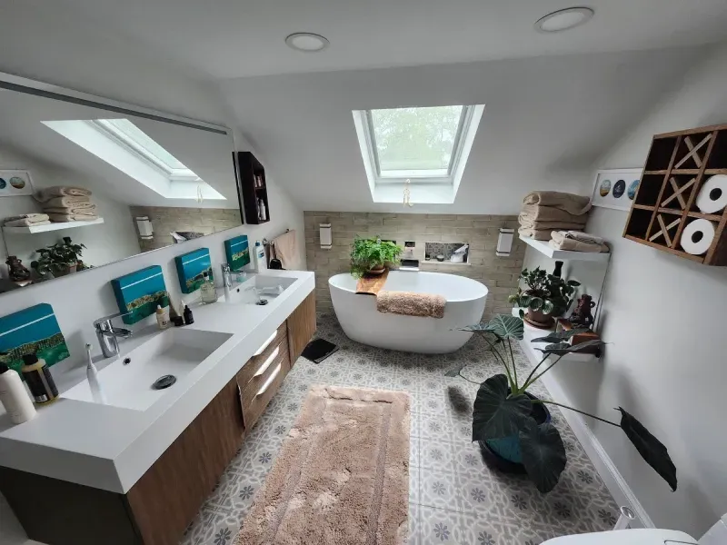 Bathroom with skylights, freestanding tub, double vanity, and patterned tile floor.