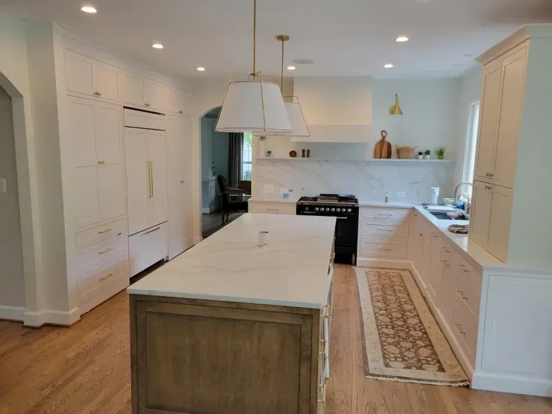 Bright kitchen with a large island and white cabinets; wood floors and countertops.