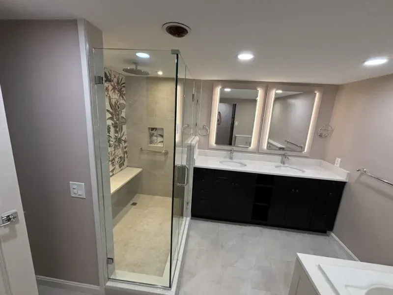 Modern bathroom with a glass shower, double vanity, and gray and white tones.