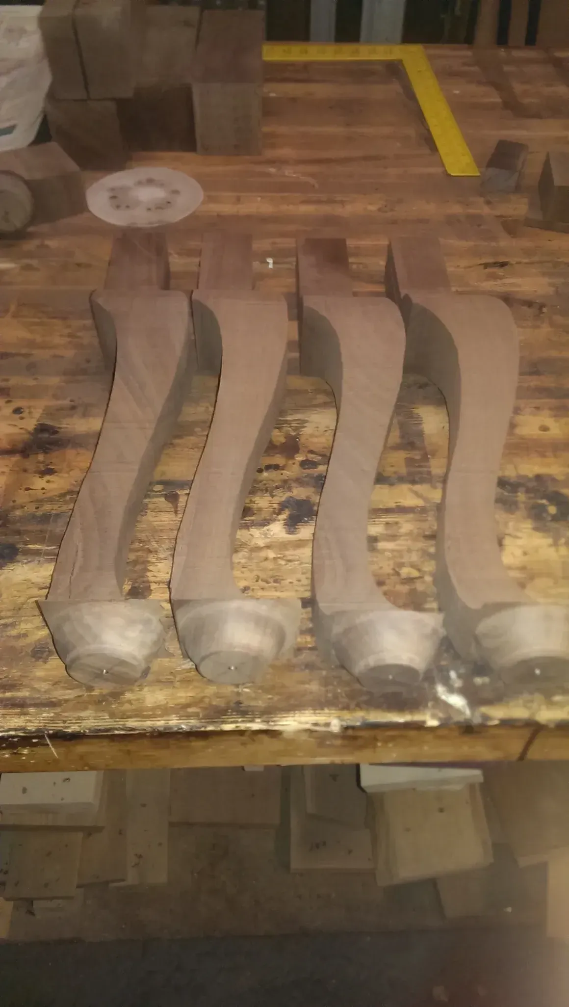 Four carved wooden furniture legs on a wooden workbench.