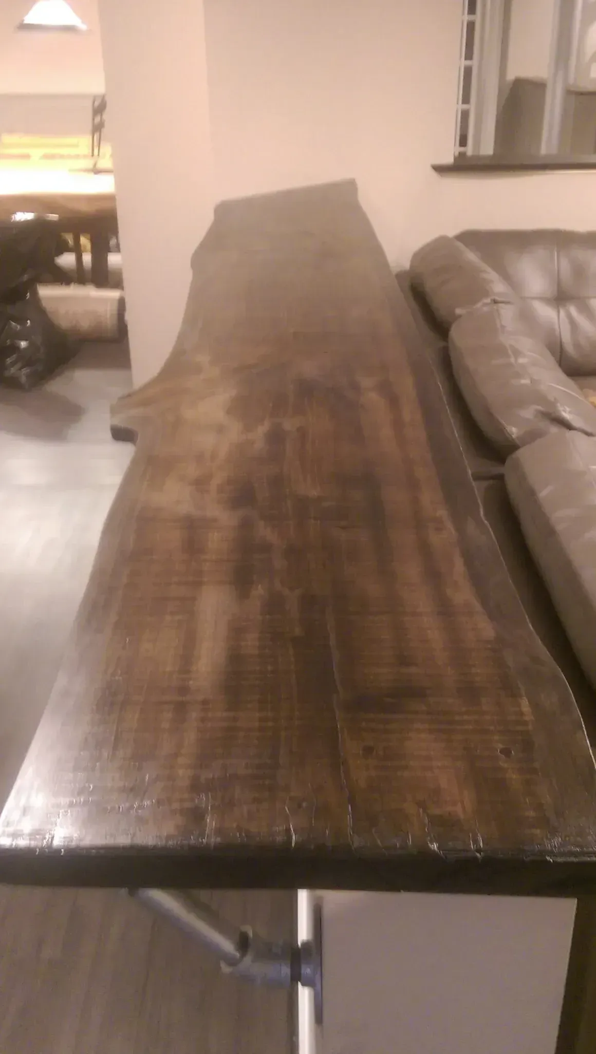 Dark wood slab table with live edge. Table is adjacent to a couch and white cabinet in a room.