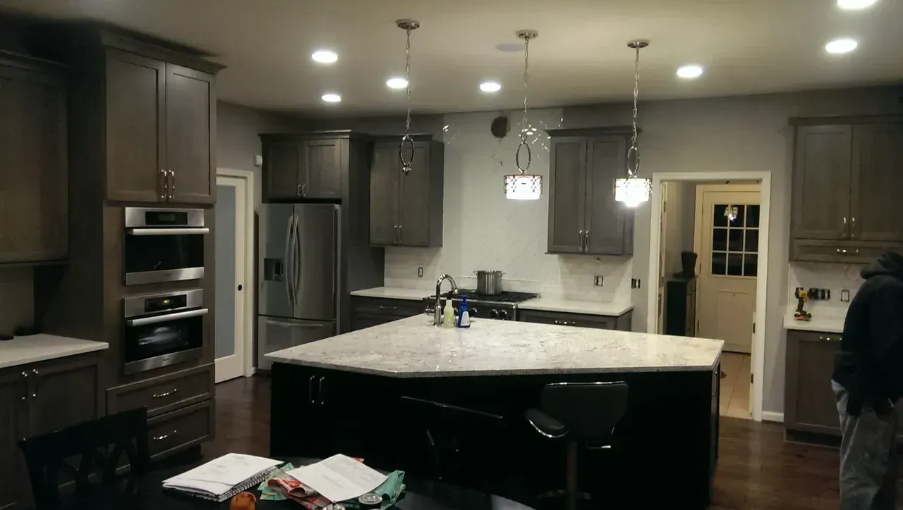 Kitchen with dark gray cabinets, stainless steel appliances, and a black island with a granite countertop.