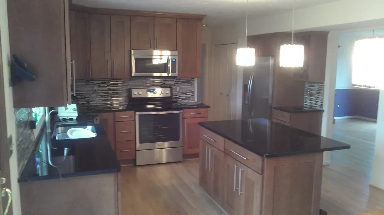 Kitchen with dark countertops, wood cabinets, stainless steel appliances, and a central island.