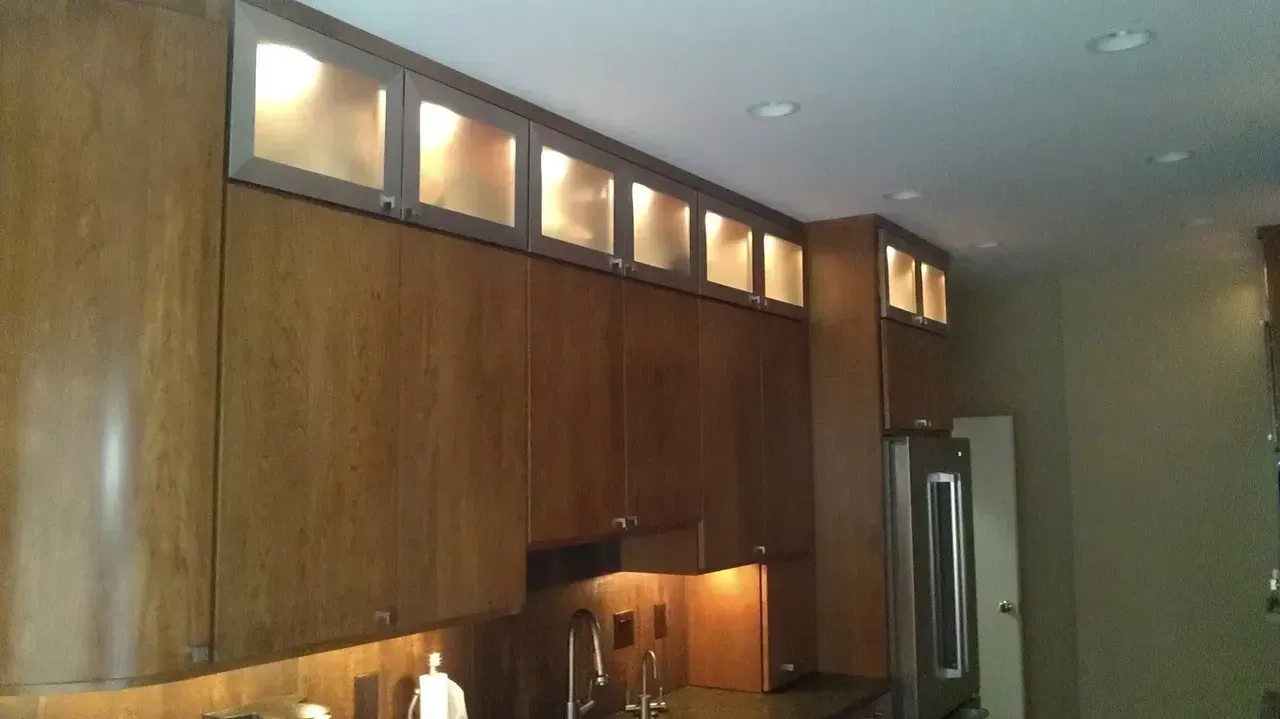 Wooden kitchen cabinets with illuminated upper display cases.