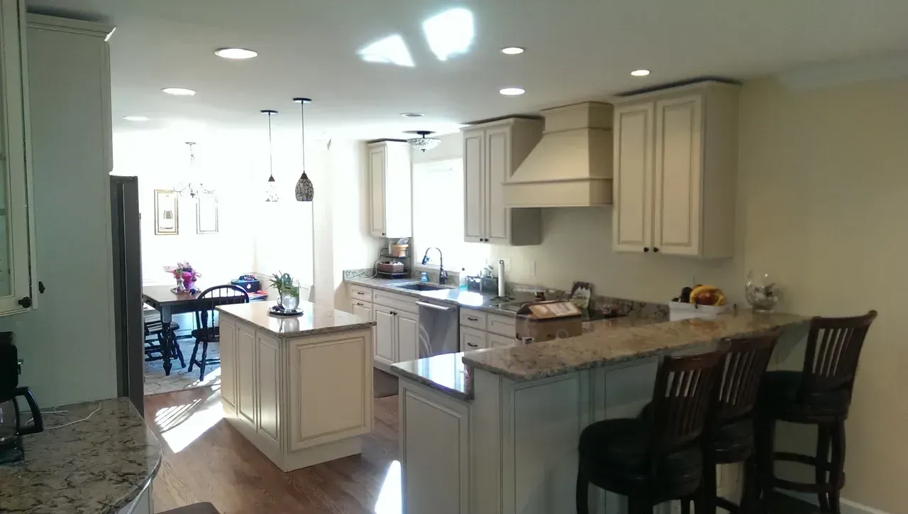 Kitchen with light-colored cabinets, granite countertops, an island, and bar seating.