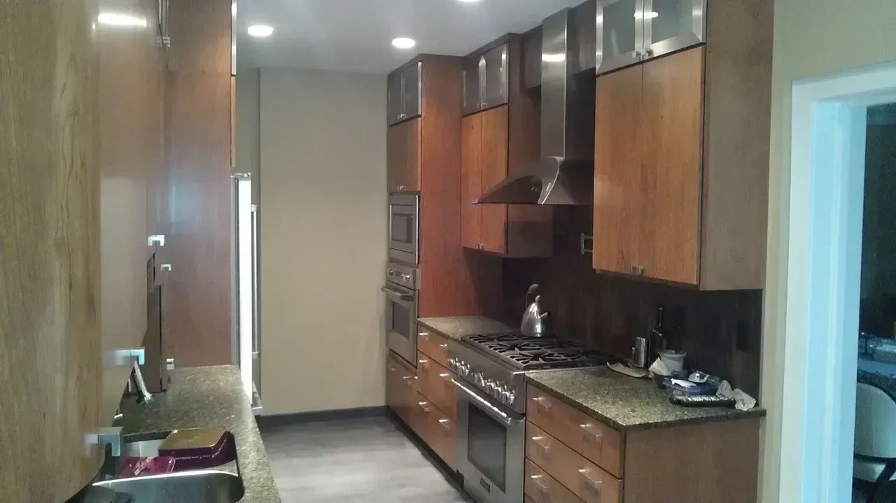Kitchen with wooden cabinets, stainless steel appliances, granite countertops, and dark floor.