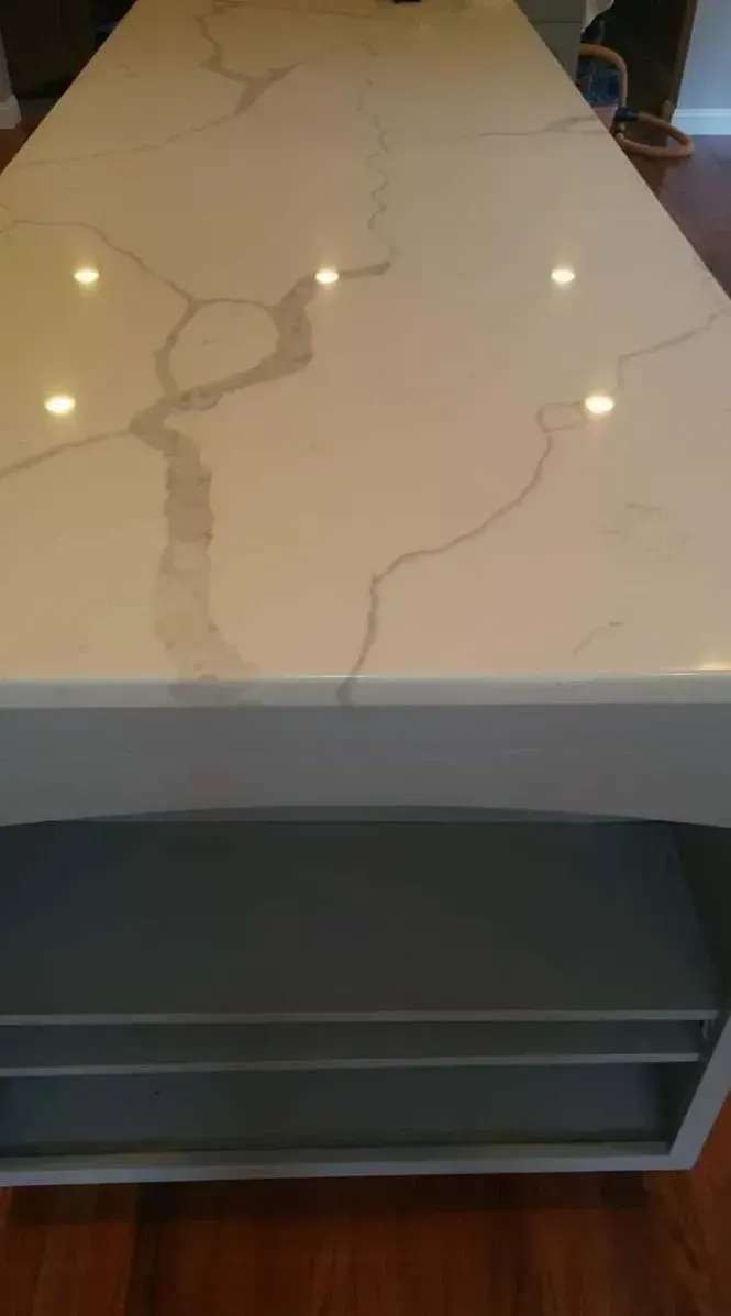 Close-up of a white quartz countertop with gray veining on a kitchen island.