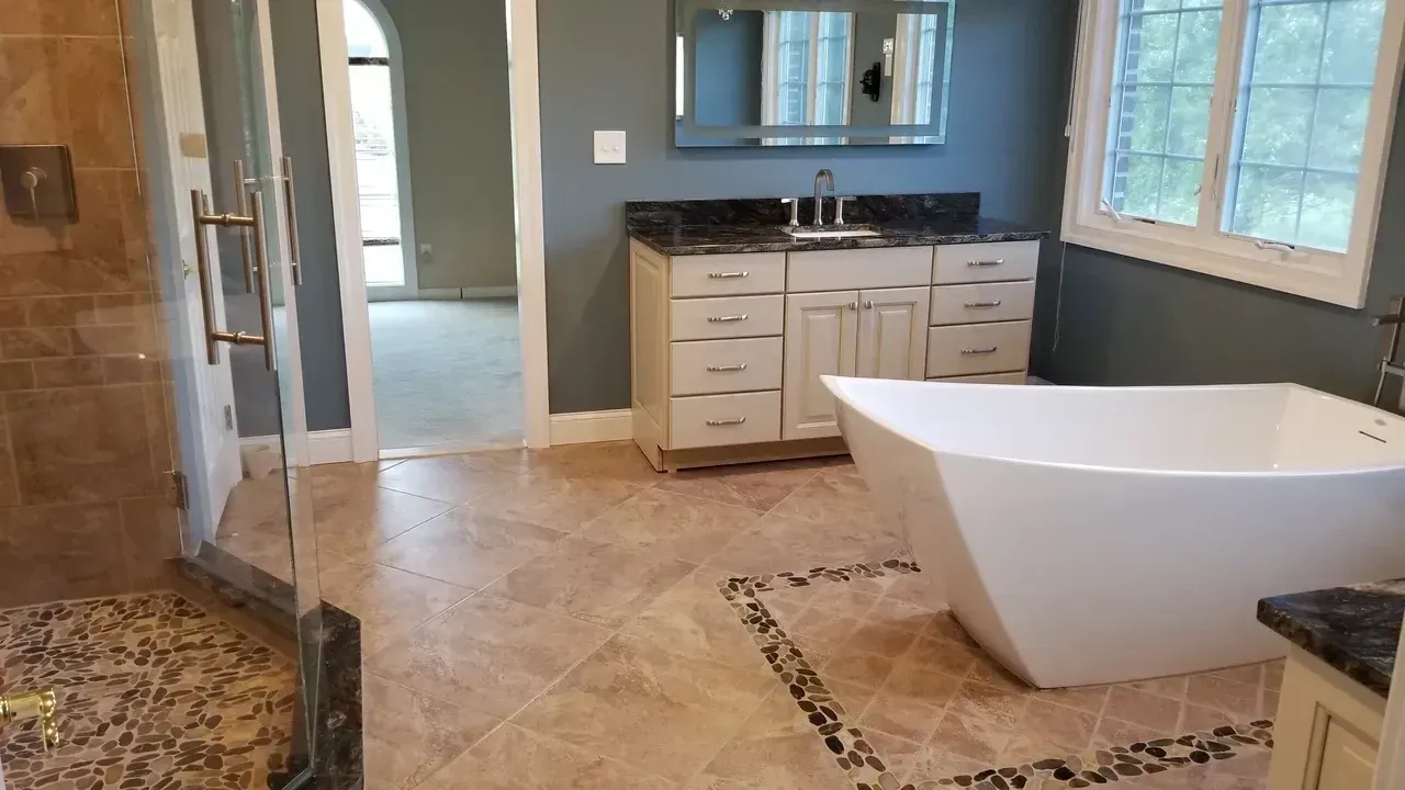 Bathroom with beige tile, white tub, vanity, and a glass shower door.