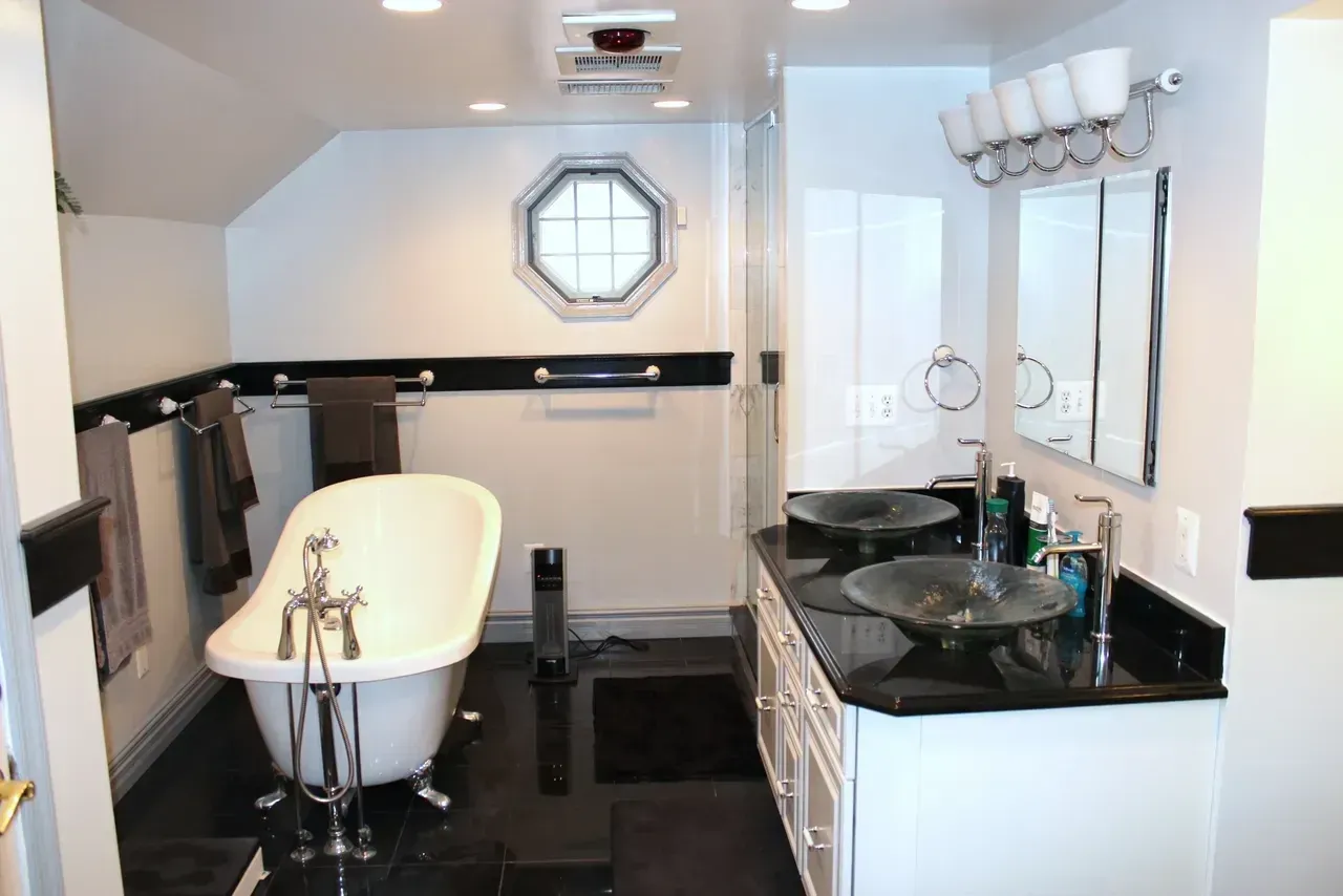 Bathroom with clawfoot tub, dual sinks, black and white color scheme.