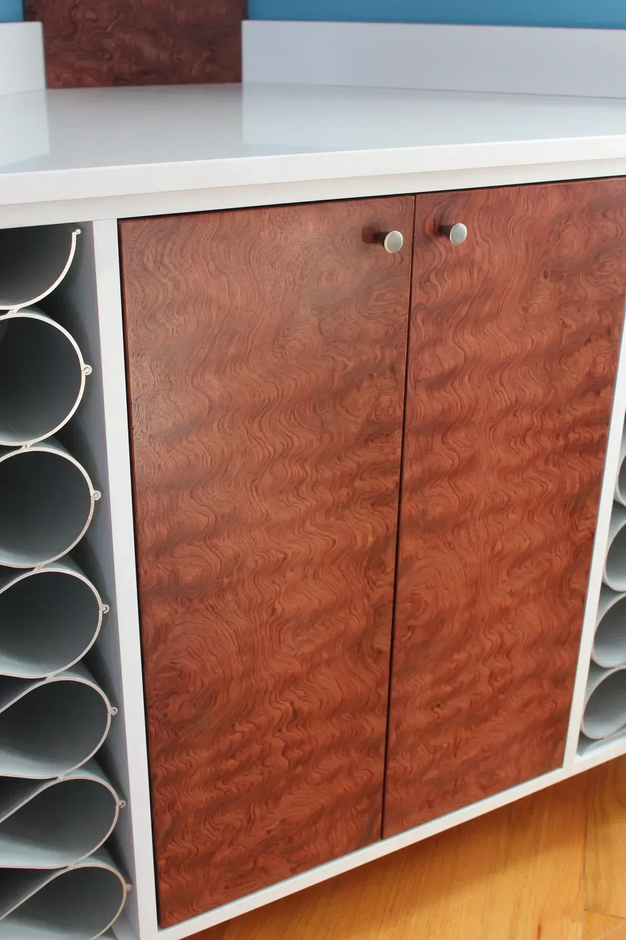 White cabinet with brown wooden doors and wine rack on the side.