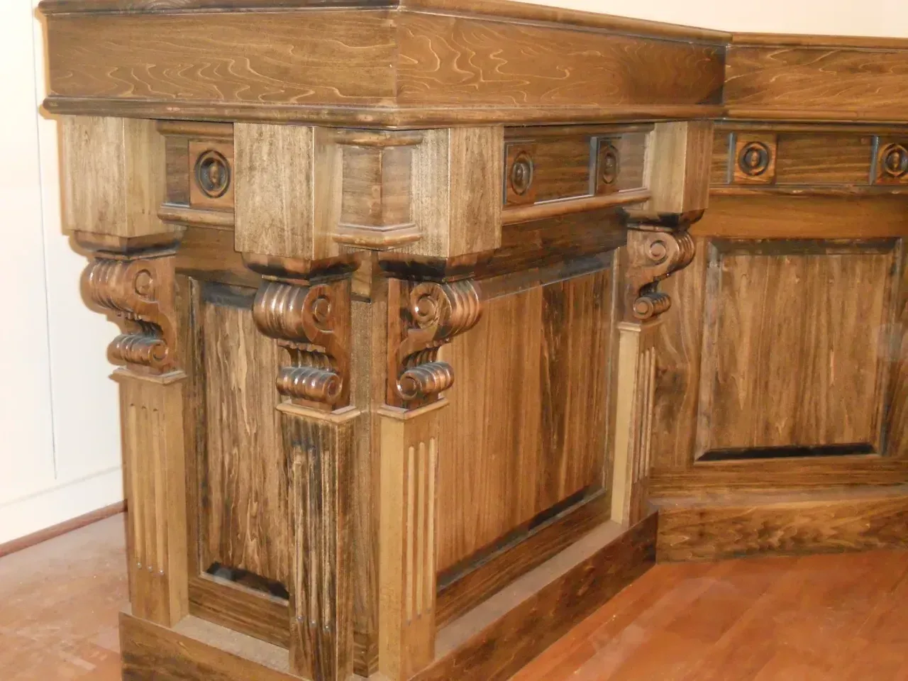 Wooden, ornate corner cabinet with carved details and a stained finish.