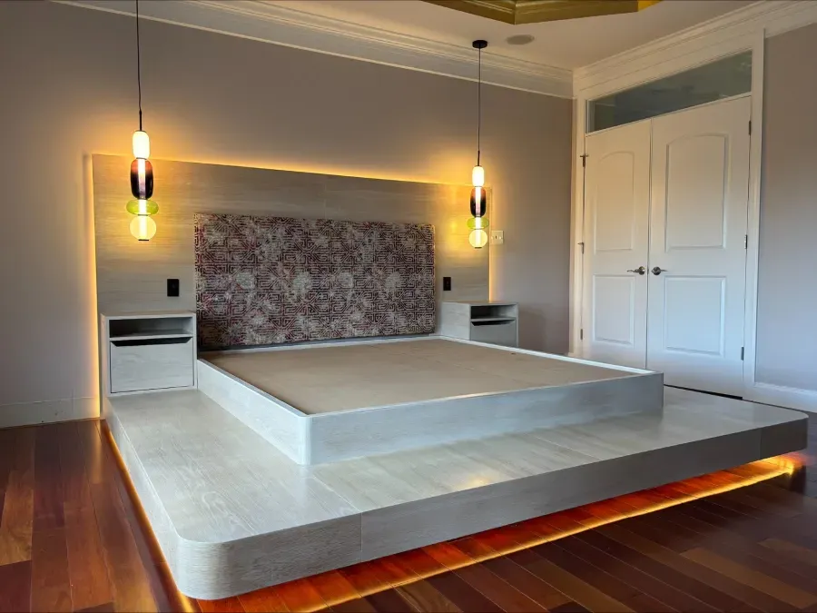 Modern bedroom with platform bed, built-in nightstands, headboard with patterned fabric, and two pendant lights.
