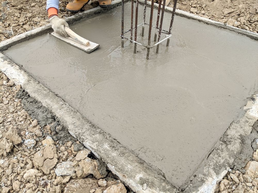 A Person is Spreading Concrete on a Concrete Slab With a Trowel — Tweed Coast Concrete Pumping in Currumbin, QLD