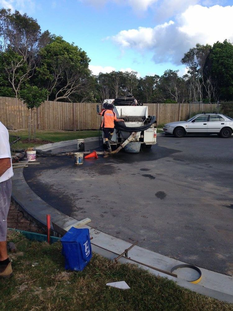 A White Car is Parked in a Parking Lot Next to a Concrete Truck — Tweed Coast Concrete Pumping in Chinderah, NSW