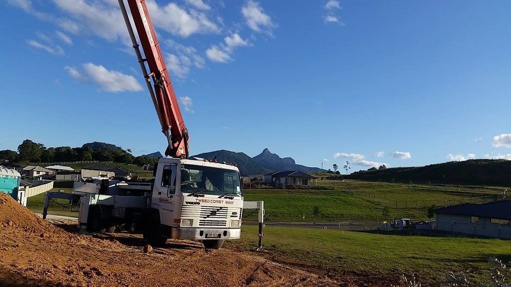 A White Truck With a Crane Attached to It is Parked in a Field — Tweed Coast Concrete Pumping in Tugun, QLD