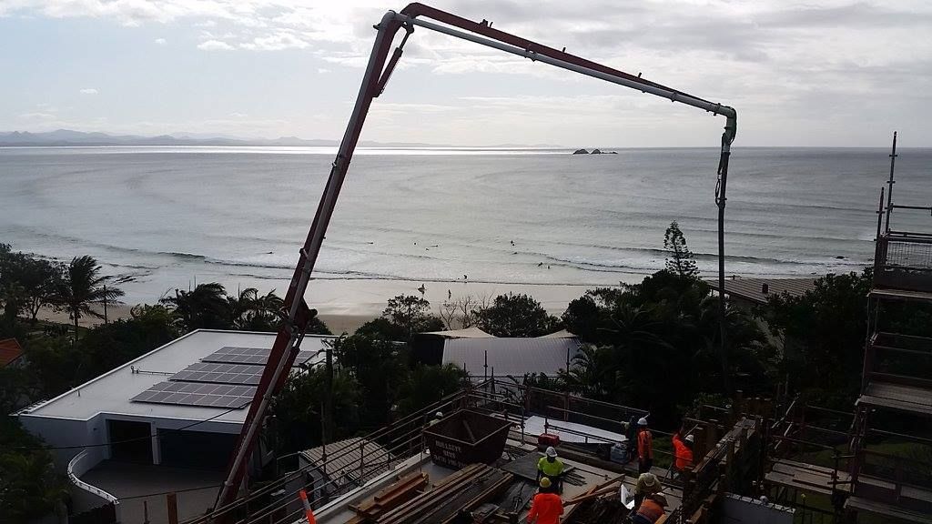 A Large Crane is Being Used to Pump Concrete Into a Building Near the Ocean — Tweed Coast Concrete Pumping in Chinderah, NSW