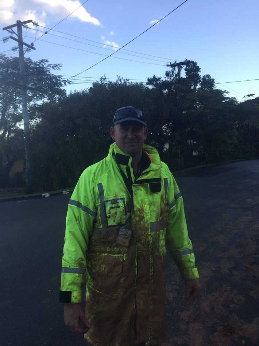 A Man in a Yellow Jacket is Standing on the Side of the Road — Tweed Coast Concrete Pumping in Chinderah, NSW
