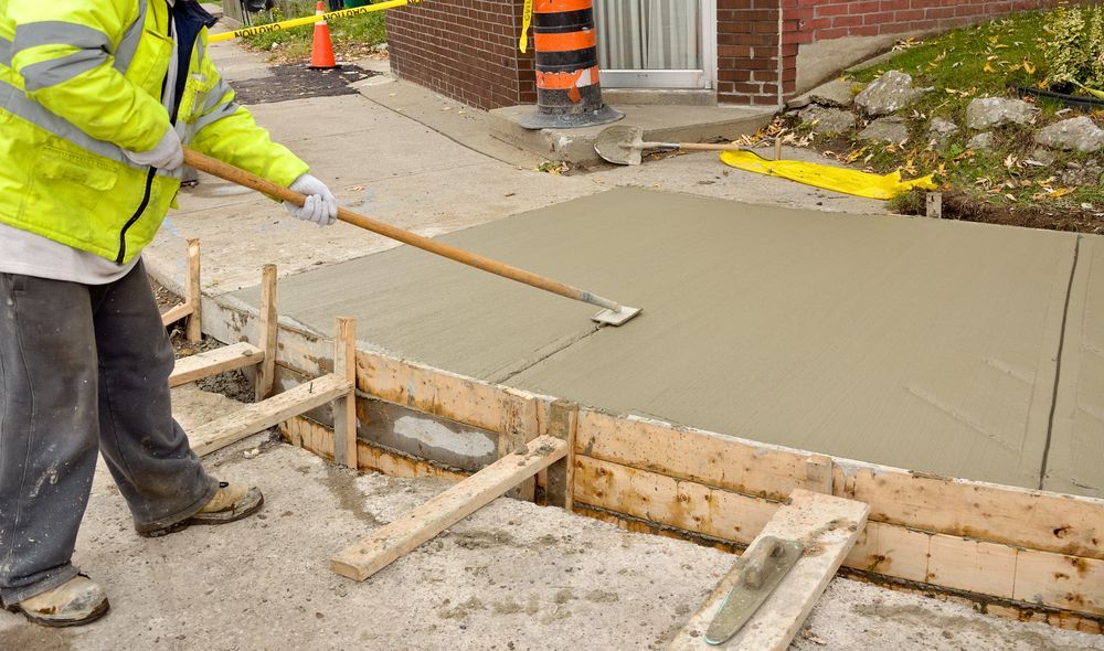 A Construction Worker is Spreading Concrete on a Sidewalk — Tweed Coast Concrete Pumping in Northern Rivers, NSW