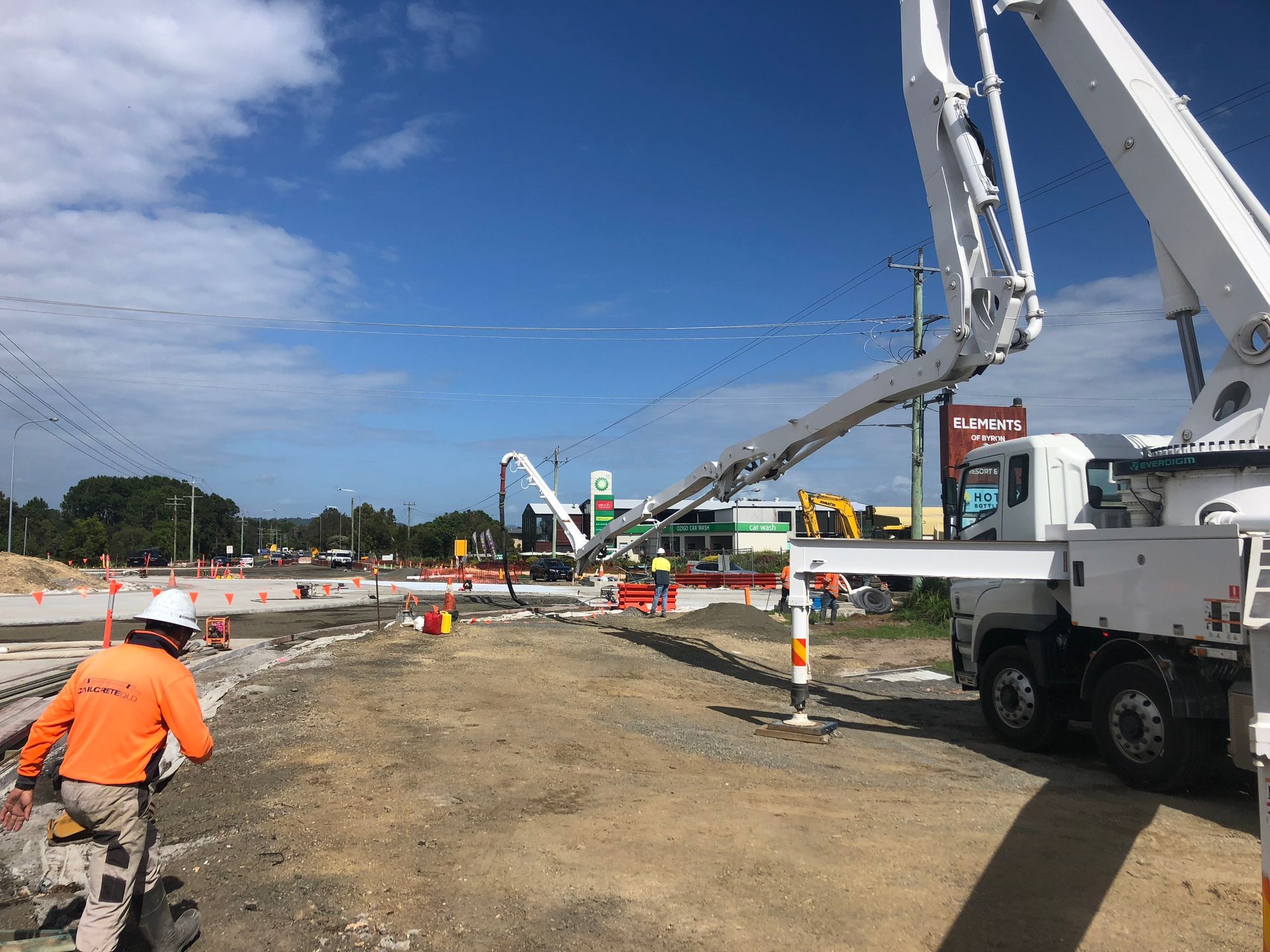 Construction site: Concrete pump pouring concrete. Worker in orange vest.