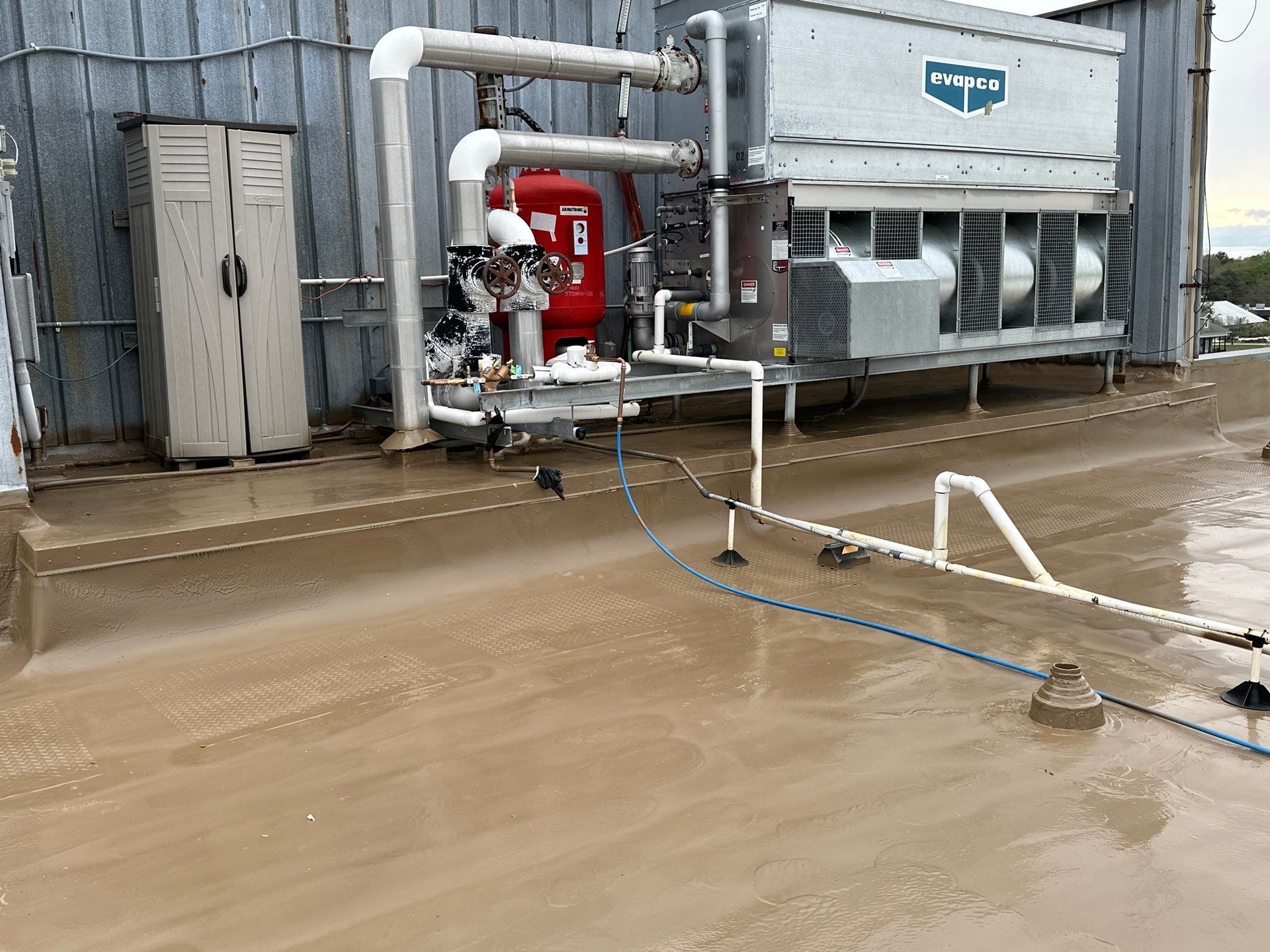 HVAC equipment on a rooftop, including pipes, a storage unit, and a large mechanical unit.