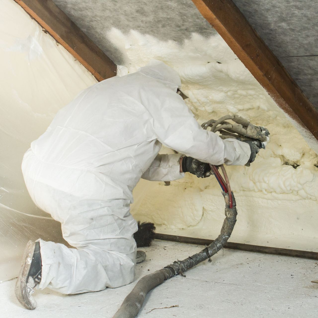 professional contractor in a protective suit during spray foam insulation installation service