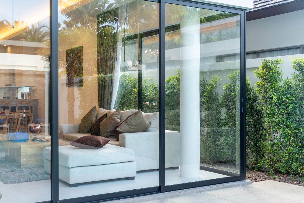 Modern Glass Patio Enclosure With a White Sofa and Cushions — ALUBEST Windows & Doors In Southport, QLD