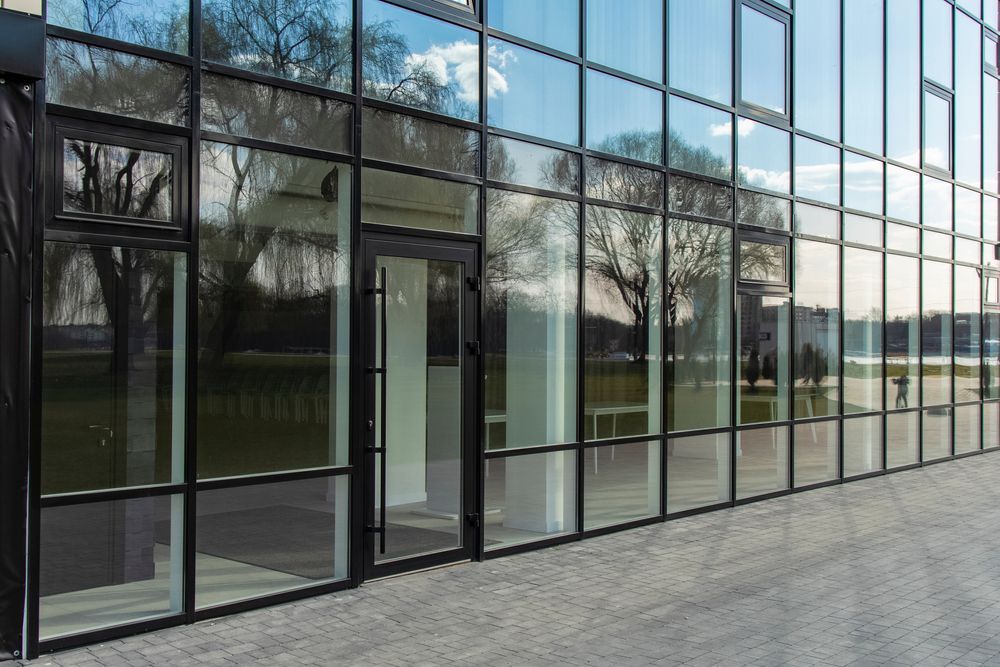 Glass-fronted Building Entrance With Reflections of Trees — ALUBEST Windows & Doors In Southport, QLD