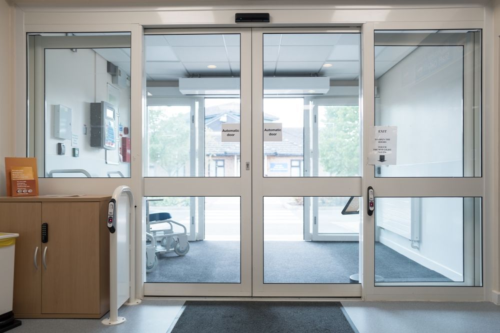 Glass Automatic Lobby Doors With a Side Cabinet — ALUBEST Windows & Doors In Southport, QLD