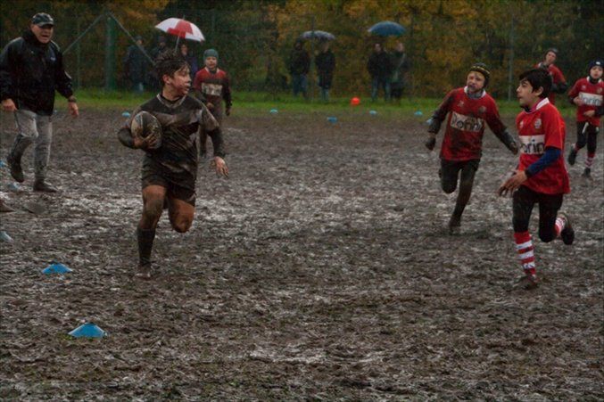 Un gruppo di ragazzi gioca a rugby su un campo fangoso.