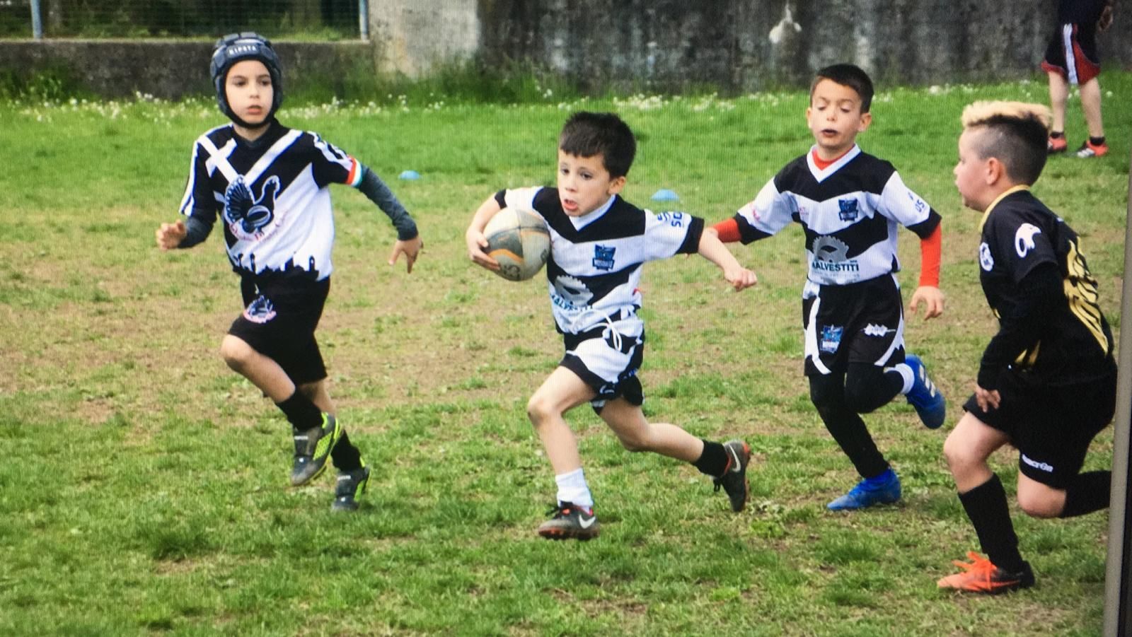 Un gruppo di ragazzi sta giocando a rugby su un campo.