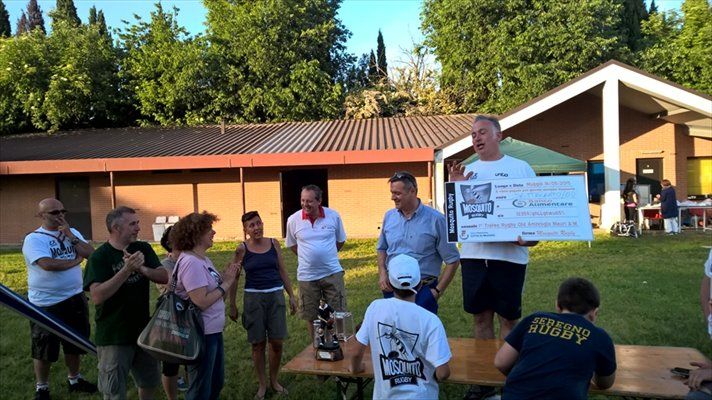 Un uomo tiene in mano un assegno di grandi dimensioni davanti a un gruppo di persone.