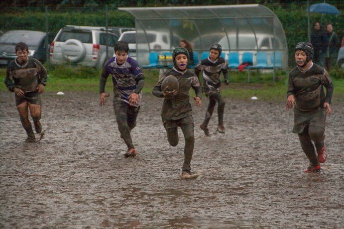 Un gruppo di giovani uomini sta giocando a rugby su un campo fangoso.