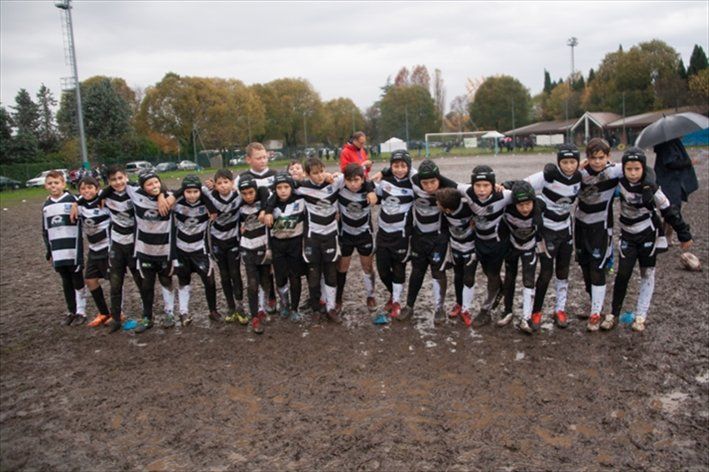Un gruppo di ragazzi posa per una foto in un campo fangoso.