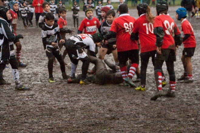 Un gruppo di bambini sta giocando a rugby nel fango.