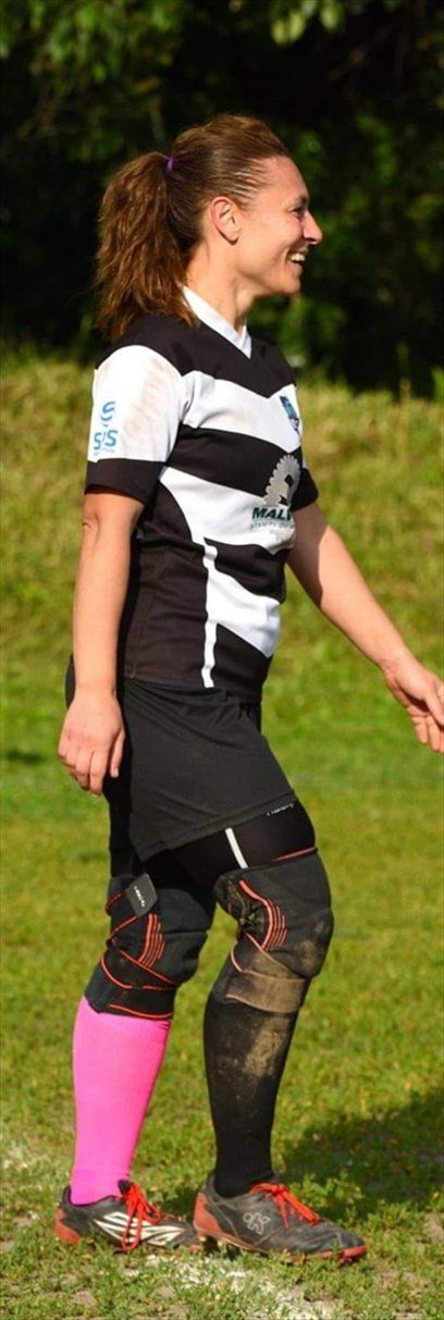 Una donna con una maglietta a righe bianche e nere e calzini rosa è in piedi in un campo.