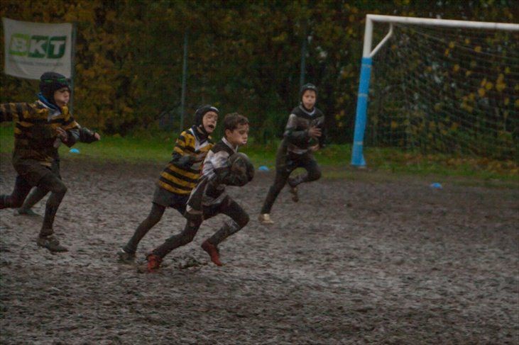 Un gruppo di ragazzi gioca a rugby su un campo fangoso.