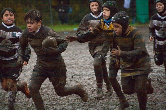 Un gruppo di ragazzi gioca a rugby nel fango.