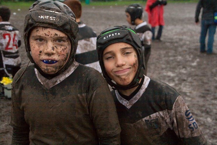 Due ragazzini che indossano maglie e caschi infangati posano per una foto.