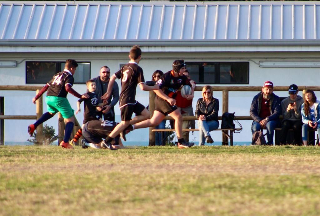 Un gruppo di ragazzi sta giocando una partita di rugby su un campo.
