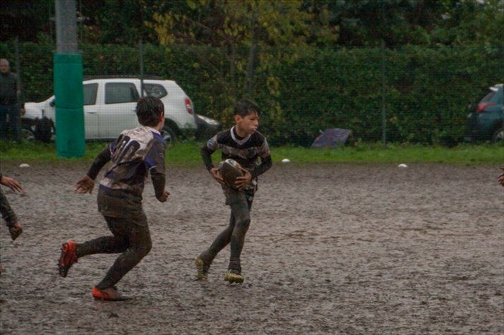 Un gruppo di ragazzi gioca a rugby su un campo fangoso.