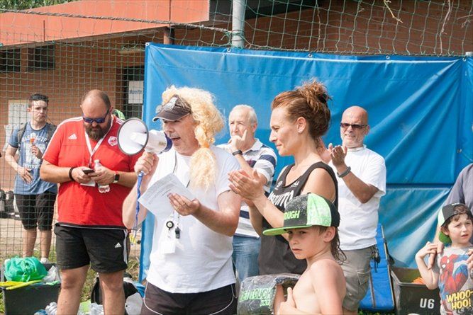 Una donna con una parrucca sta tenendo un discorso davanti a un gruppo di persone.