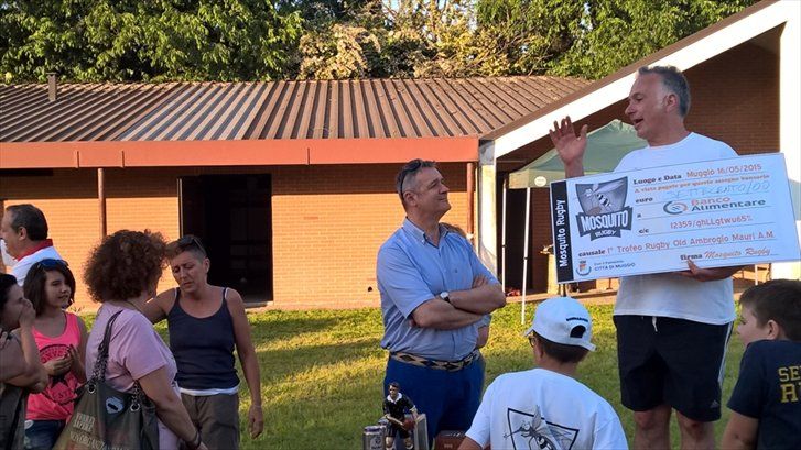 Un uomo tiene in mano un assegno di grandi dimensioni davanti a un gruppo di persone.