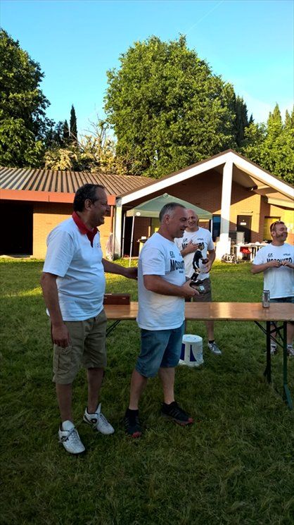 Un gruppo di uomini è in piedi in un campo erboso di fronte a un edificio.