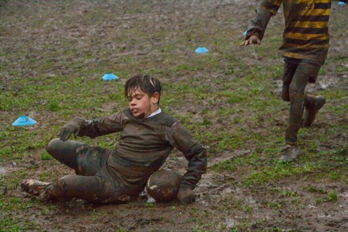 Un ragazzino giace a terra nel fango.