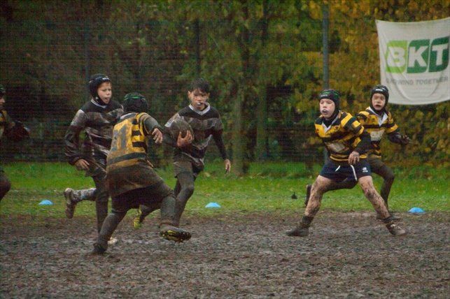 Un gruppo di giovani sta giocando una partita di rugby su un campo fangoso.