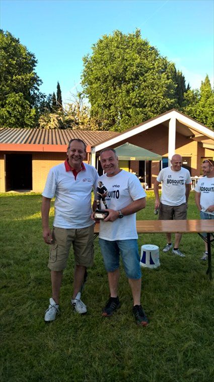Due uomini sono in piedi uno accanto all'altro in un campo erboso e tengono in mano un trofeo.