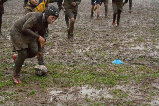 Un gruppo di persone sta giocando a calcio in un campo fangoso.