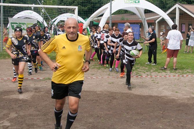 Un uomo con una maglietta gialla corre davanti a un gruppo di giocatori di calcio