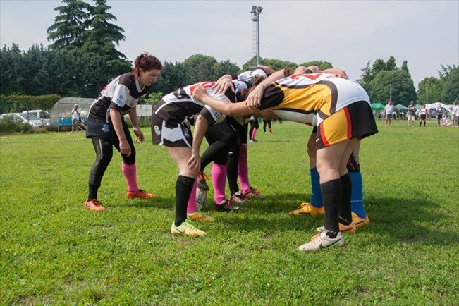 Un gruppo di giocatrici di rugby sono ammassate insieme su un campo.