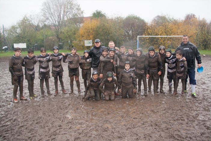 Un gruppo di bambini posa per una foto in un campo fangoso.